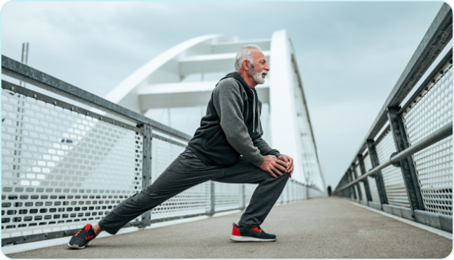 active-aging-mobility-exercise Older adult man stretching his legs on a pedestrian bridge during an outdoor workout.