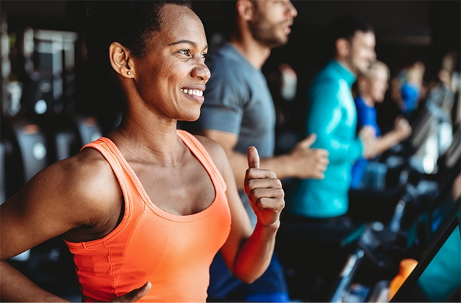 Female running on a treadmill at a gym with other treadmill runners