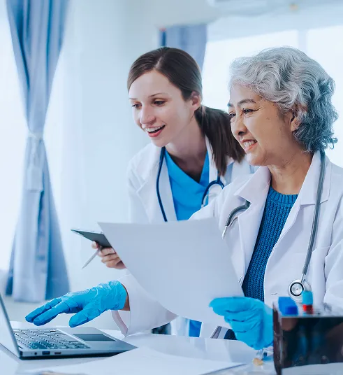 healthcare-professionals-clinical-research-review Two healthcare professionals review research information on a laptop in a clinical setting.